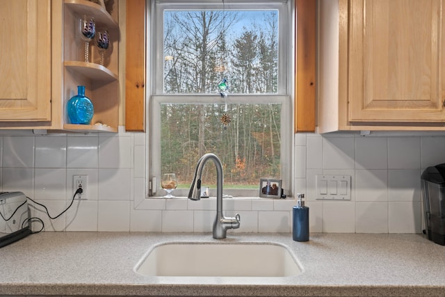 kitchen featuring light brown cabinetry, tasteful backsplash, light stone counters, and sink