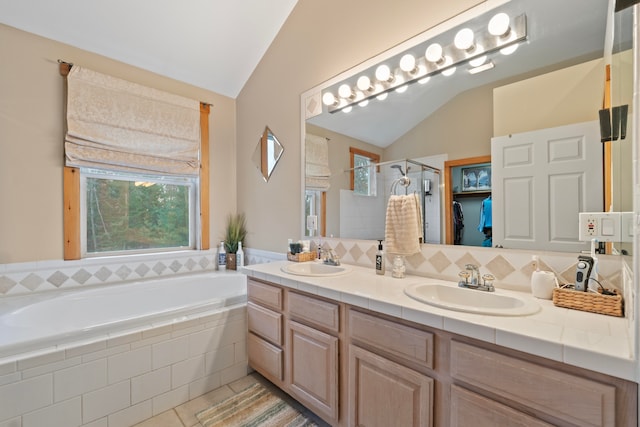 bathroom with plus walk in shower, vanity, vaulted ceiling, and tile patterned flooring