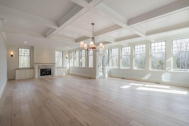 unfurnished living room with a chandelier, beamed ceiling, coffered ceiling, and light wood-type flooring