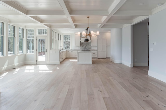 kitchen with white cabinets, coffered ceiling, custom range hood, pendant lighting, and light wood-type flooring