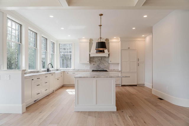 kitchen featuring a kitchen island, light wood-type flooring, light stone countertops, and a healthy amount of sunlight