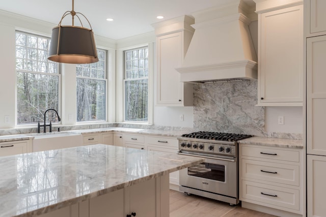 kitchen with light stone countertops, a wealth of natural light, premium range hood, and high end range