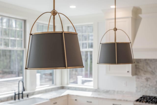 details featuring sink, light stone counters, tasteful backsplash, crown molding, and white cabinets