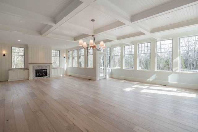 unfurnished living room with light wood-type flooring, beamed ceiling, a high end fireplace, and coffered ceiling