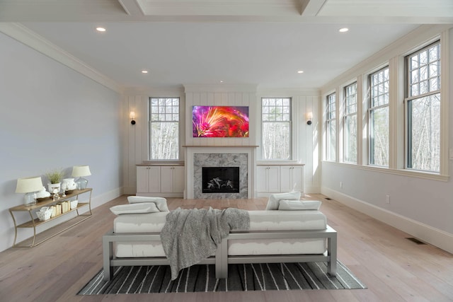 living room with ornamental molding, a healthy amount of sunlight, and light hardwood / wood-style flooring