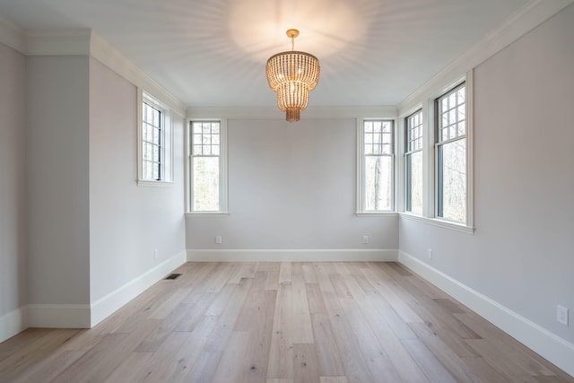 empty room featuring light wood-type flooring, crown molding, and a notable chandelier