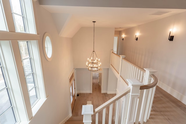 staircase featuring wood-type flooring and a notable chandelier