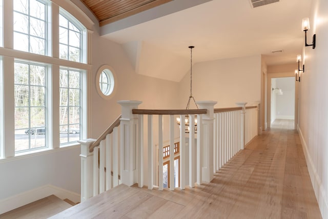 hallway featuring light wood-type flooring, a wealth of natural light, and vaulted ceiling