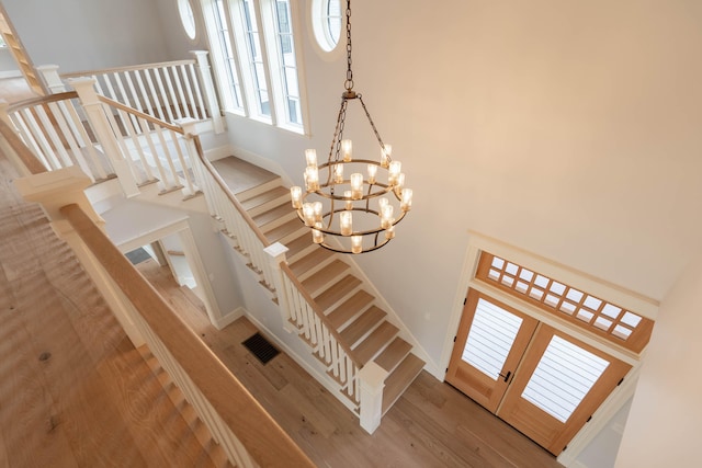 stairway featuring wood-type flooring, a chandelier, and french doors