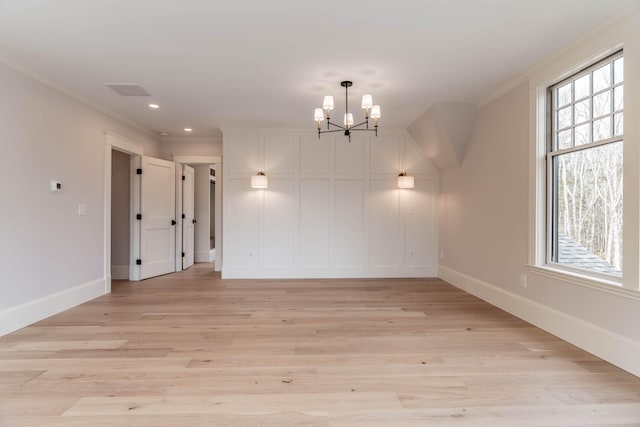 spare room with light wood-type flooring, an inviting chandelier, and ornamental molding