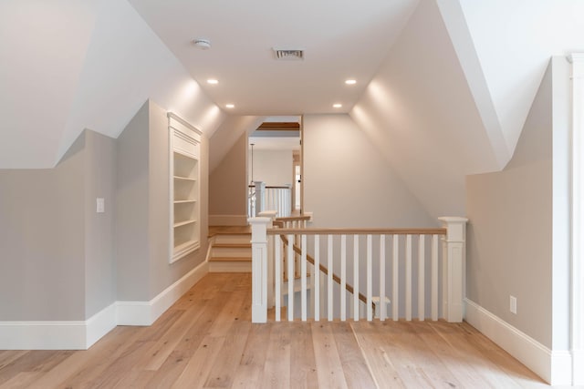 bonus room featuring built in shelves, lofted ceiling, and light hardwood / wood-style floors