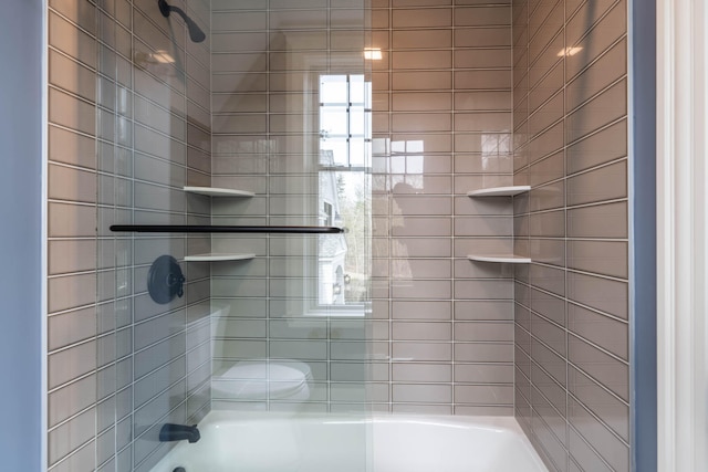 bathroom with toilet and tiled shower / bath