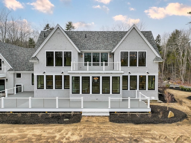 back house at dusk with a sunroom and a deck