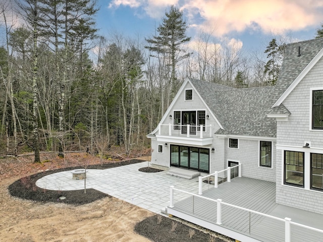 back house at dusk with a wooden deck and a patio