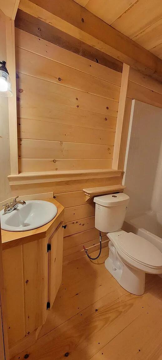 bathroom with hardwood / wood-style floors, vanity, wooden walls, and toilet