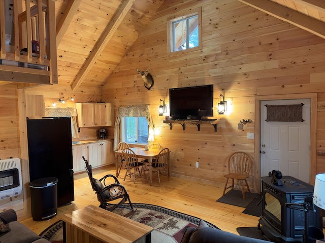 living room with light hardwood / wood-style floors, wood walls, beam ceiling, and heating unit