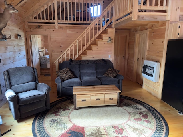 living room with wood walls, heating unit, and light hardwood / wood-style floors