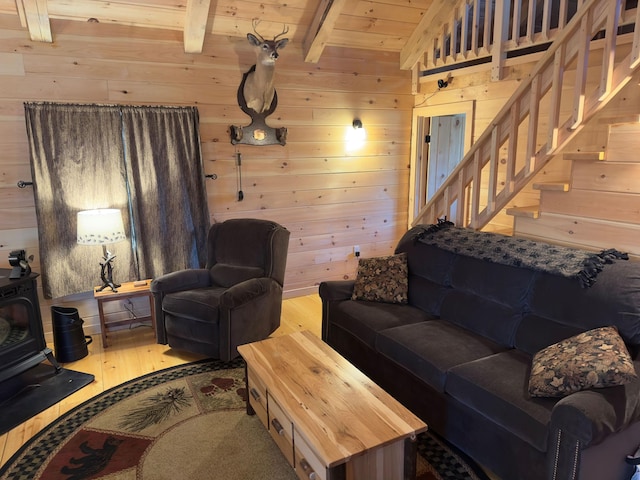 living room with lofted ceiling with beams, a wood stove, wooden walls, hardwood / wood-style floors, and wood ceiling