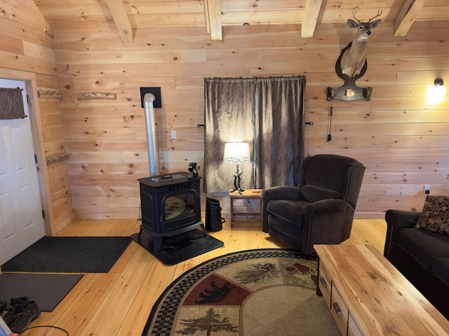 living room featuring a wood stove, lofted ceiling with beams, wooden walls, and hardwood / wood-style flooring