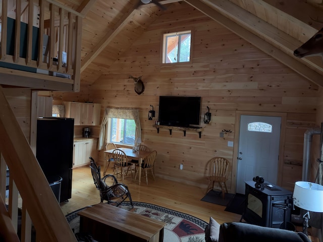 living room with lofted ceiling with beams, wooden walls, light wood-type flooring, and wood ceiling