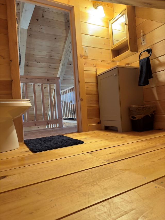 additional living space with wood walls, hardwood / wood-style flooring, and lofted ceiling