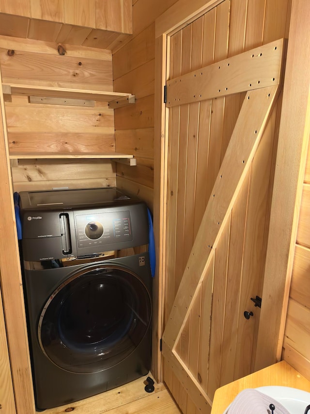 clothes washing area featuring washer / dryer and wooden walls