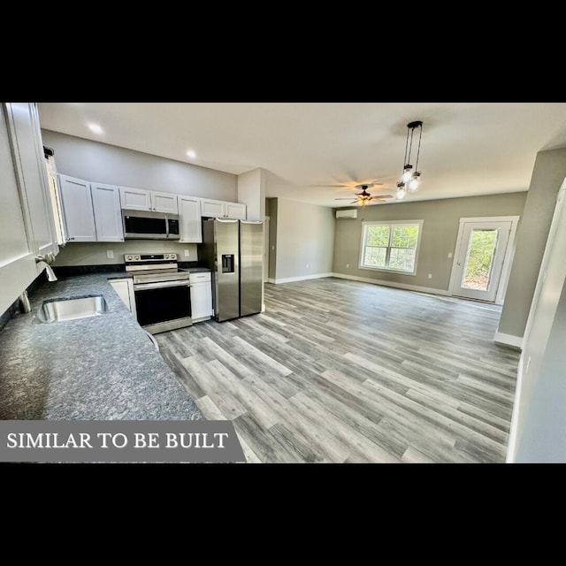 kitchen featuring white cabinetry, sink, stainless steel appliances, light hardwood / wood-style flooring, and decorative light fixtures