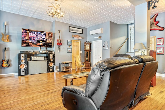 living room with a notable chandelier, light hardwood / wood-style flooring, and a wall unit AC