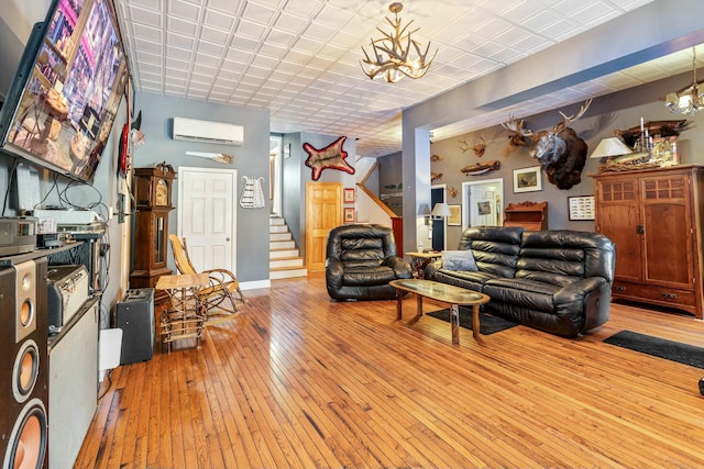 living room with an inviting chandelier, light wood-type flooring, and an AC wall unit