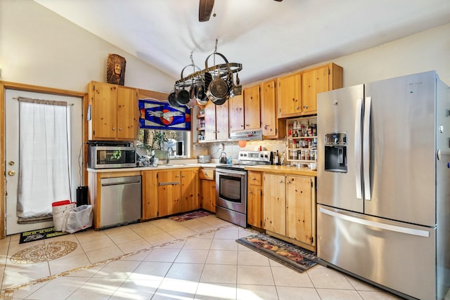 kitchen with sink, an inviting chandelier, vaulted ceiling, light tile patterned floors, and appliances with stainless steel finishes