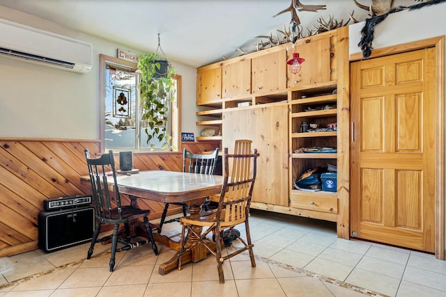 dining area featuring a wall mounted air conditioner, wood walls, and light tile patterned flooring