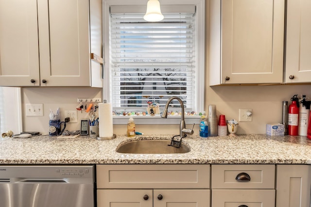 kitchen featuring dishwasher, sink, and light stone countertops