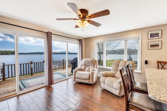 living room featuring a water view, dark hardwood / wood-style floors, and ceiling fan