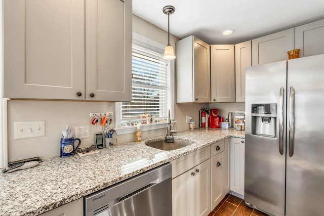 kitchen with dark wood-type flooring, sink, light stone countertops, pendant lighting, and appliances with stainless steel finishes