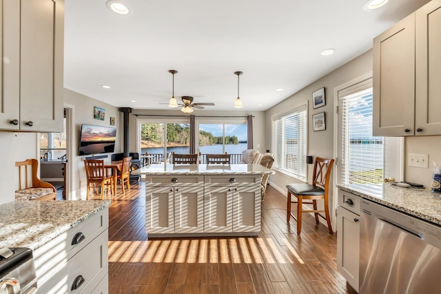 kitchen with stainless steel appliances, dark wood-type flooring, hanging light fixtures, ceiling fan, and light stone countertops