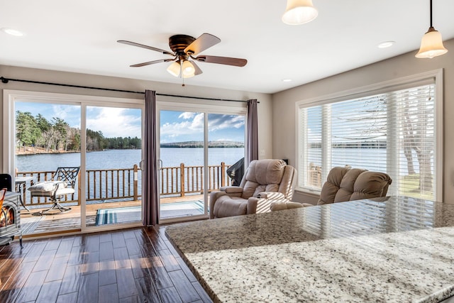 dining area with ceiling fan, a wealth of natural light, dark hardwood / wood-style floors, and a water view