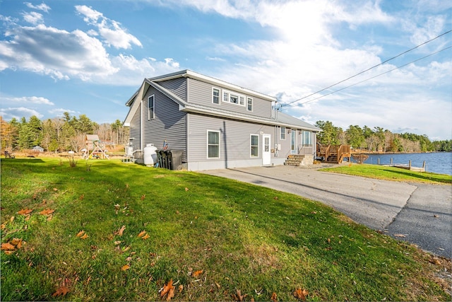 back of property with a yard and a water view