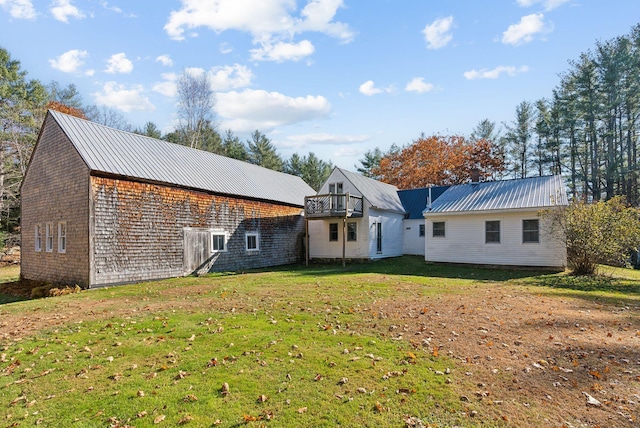 back of house with a balcony and a lawn