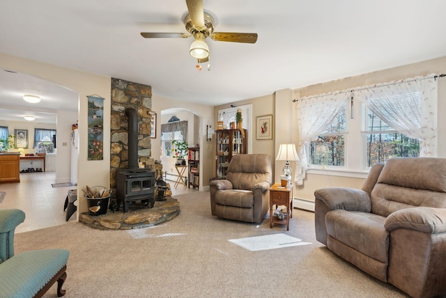 living room featuring ceiling fan, a wood stove, and baseboard heating