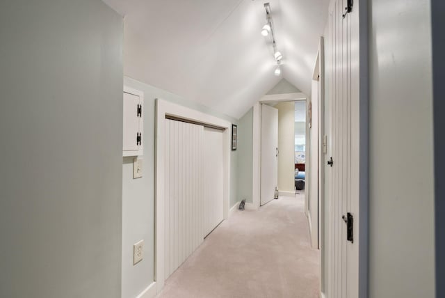 corridor featuring light carpet, track lighting, and lofted ceiling