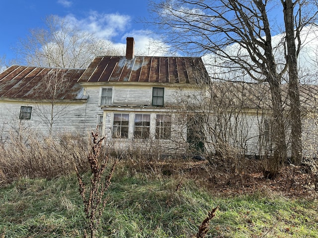 rear view of house with metal roof, a standing seam roof, and a chimney