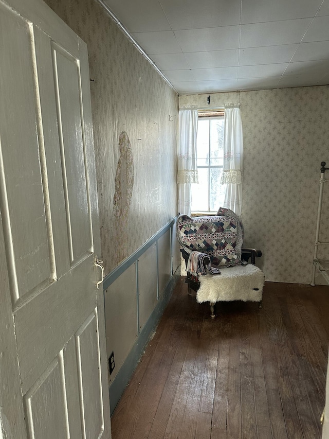 unfurnished room featuring wallpapered walls, hardwood / wood-style flooring, and wainscoting