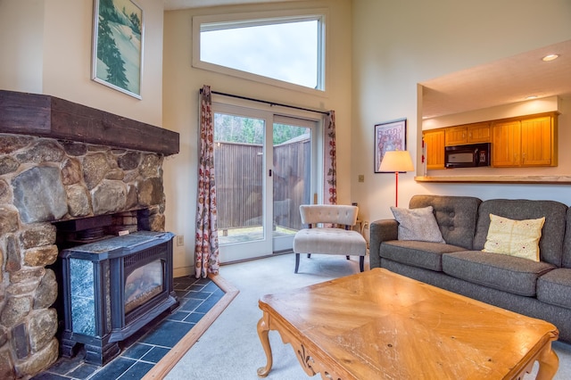 carpeted living room with a wood stove and a high ceiling