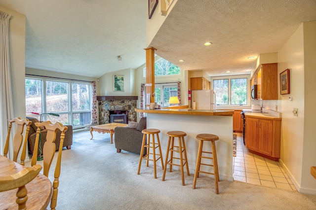 kitchen featuring a stone fireplace, white refrigerator, a textured ceiling, light carpet, and lofted ceiling