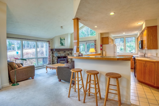 kitchen with vaulted ceiling, light carpet, a textured ceiling, white fridge, and a fireplace