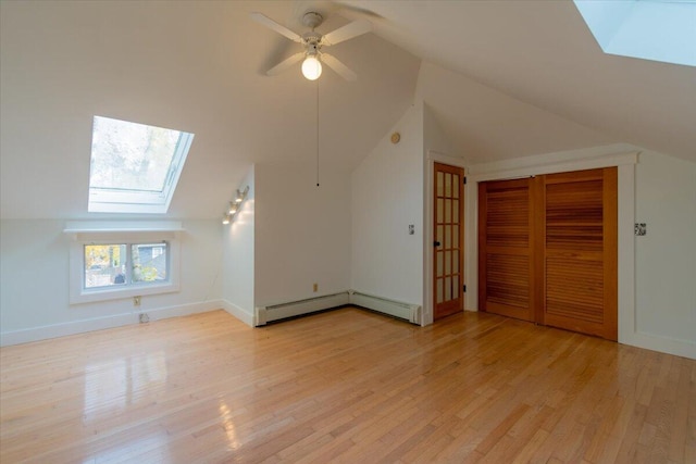 bonus room with light wood-type flooring, ceiling fan, and vaulted ceiling with skylight