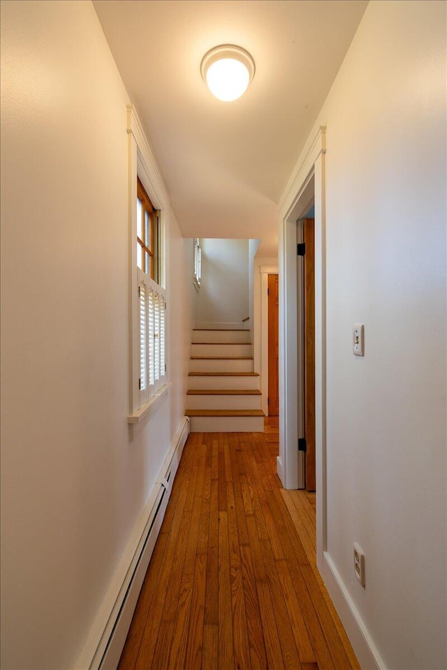 corridor with a baseboard radiator and light hardwood / wood-style flooring