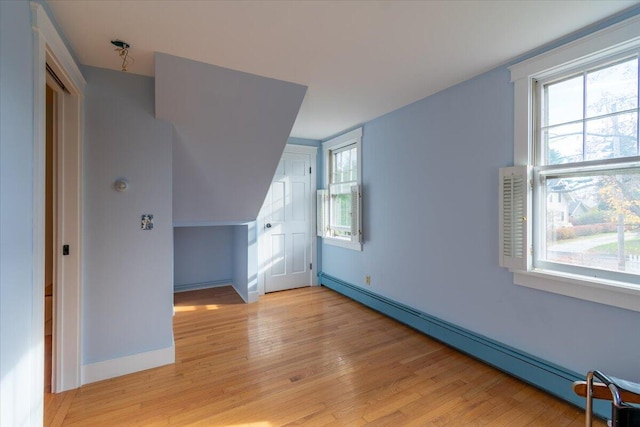 additional living space featuring baseboard heating and light hardwood / wood-style flooring