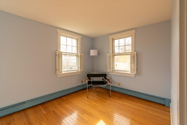 spare room with baseboard heating, light hardwood / wood-style flooring, and a healthy amount of sunlight