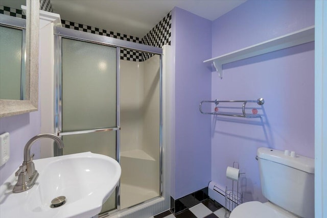 bathroom with a shower with door, sink, a baseboard heating unit, and toilet